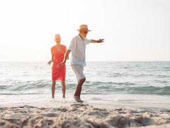 Lächelndes Seniorenpärchen spazieren am Strand entlang